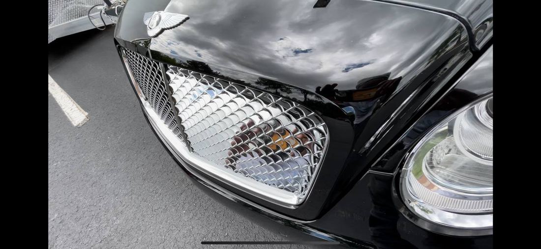 Chrome grille and headlight detail on a Bentley, polished to a bright finish.