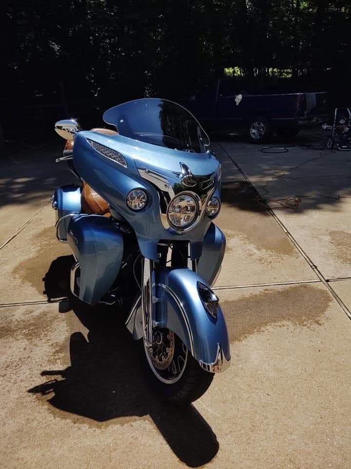 Full ceramic coating detail on a blue Harley-Davidson touring motorcycle, gleaming in driveway sunlight.