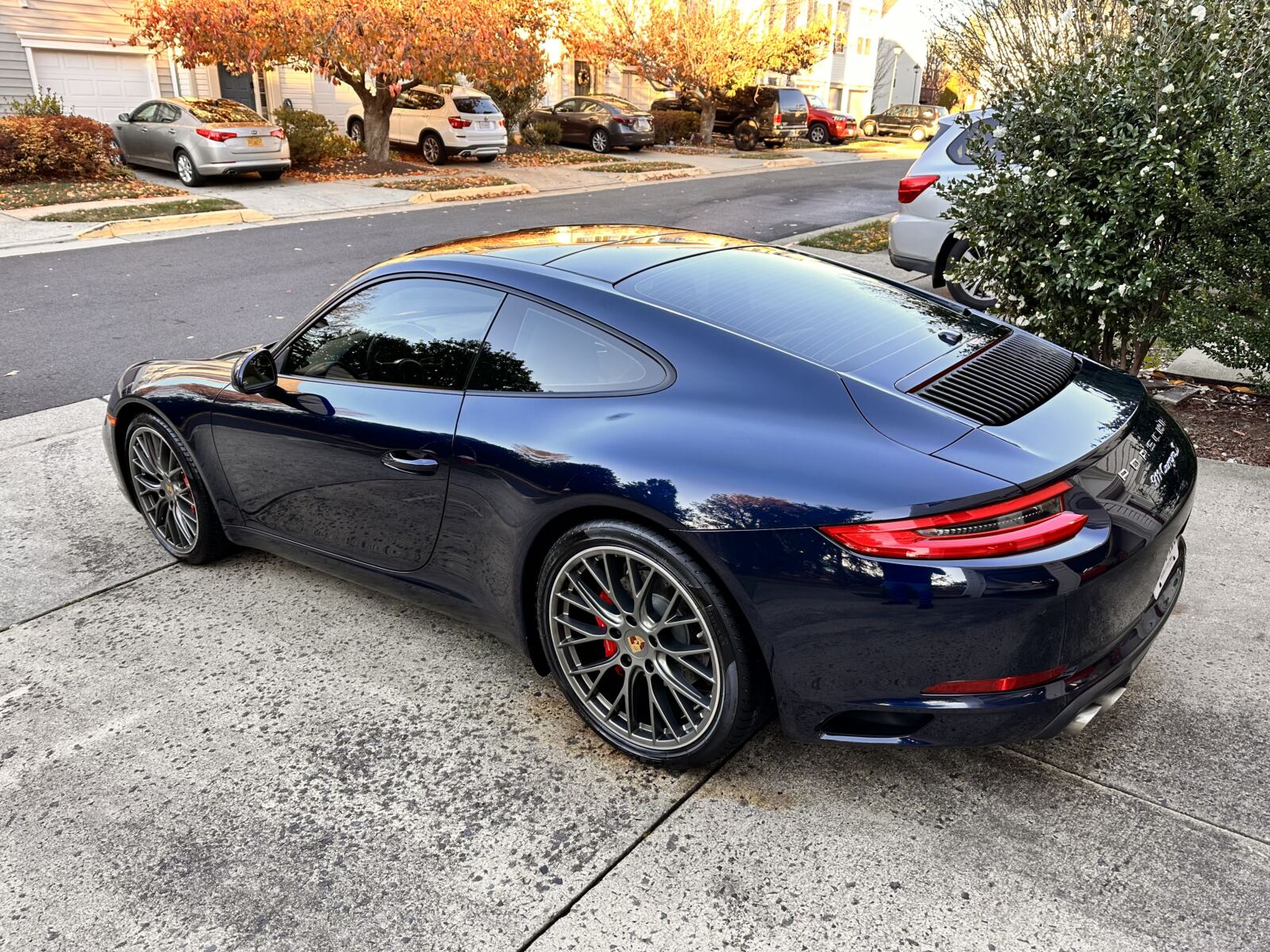 Ceramic coating application on a dark blue Porsche 911 in a residential driveway, showcasing premium paint protection and glossy finish.