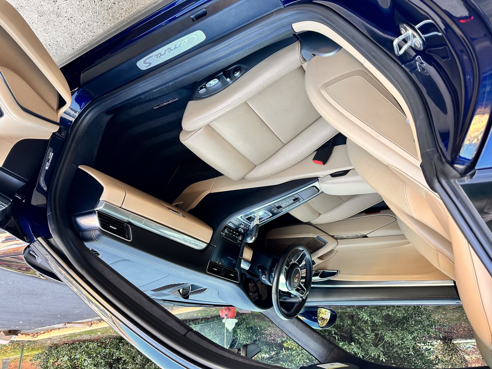 Interior detailing on a blue Porsche 911 Carrera, showcasing cream leather seats restored to pristine condition.